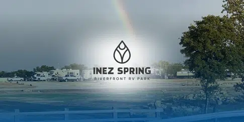 Riverside RV sites at Inez Spring Riverfront RV Park with a rainbow overhead.
