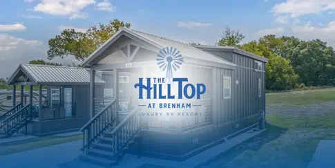 Modern cabins at The Hilltop at Brenham Luxury RV Resort beside open grassy areas and trees.