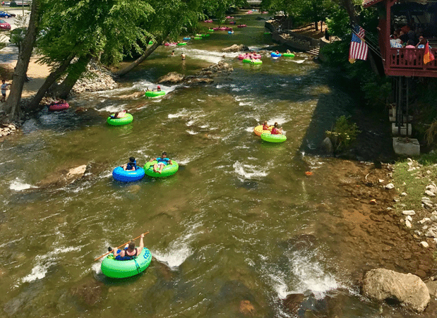 Visitors floating on inner tubes along the Chattahoochee River surrounded by trees and scenic river views.
