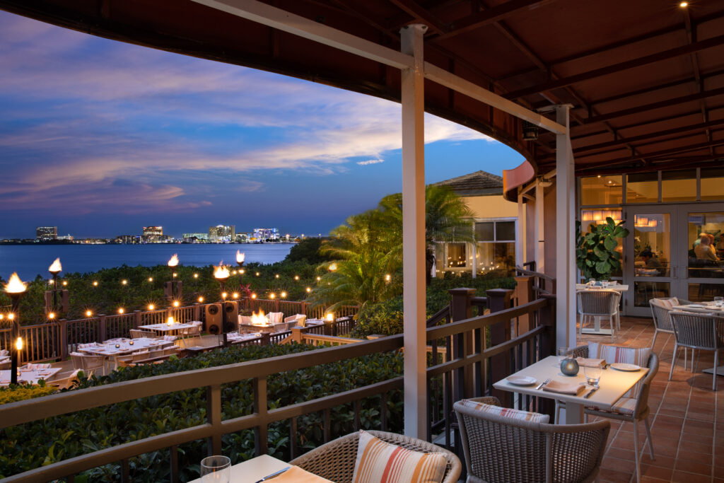 Waterfront dining near Tampa campgrounds with outdoor seating, Gulf Coast sunset views, boats docked nearby, and RV travelers enjoying seafood by the water in 2026