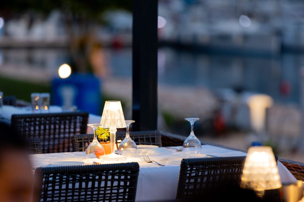 Elegant waterfront dining table overlooking a marina at sunset.