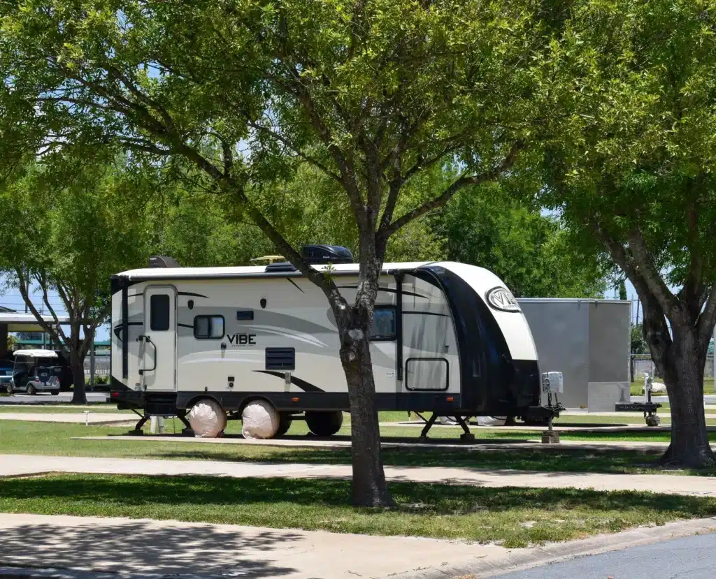 Travel trailer at a shaded RV site in Alamo Rose RV Park