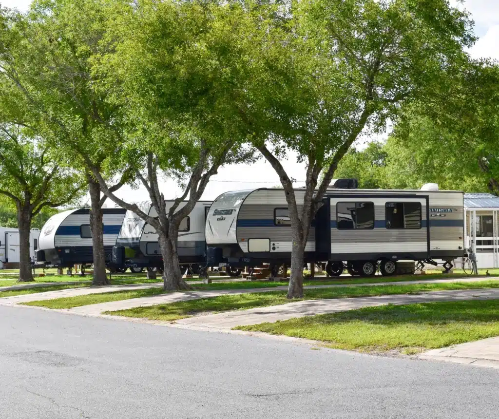 RV trailers parked on spacious campsites beneath mature shade trees at Winter Ranch RV Resort.