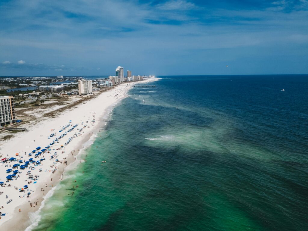 Aerial view of sandy beach, ocean waves, and beachfront buildings