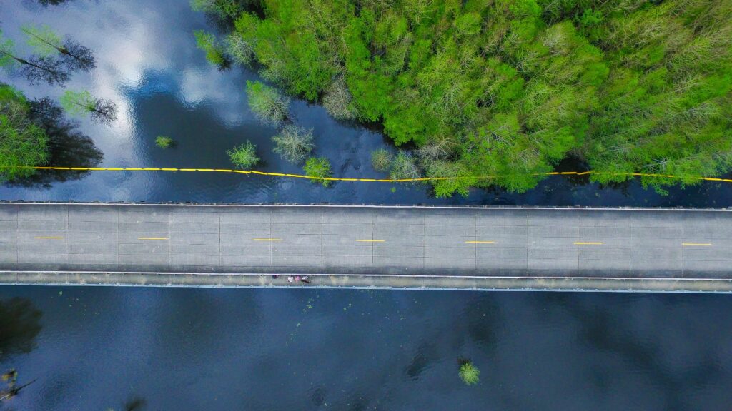 Top-down view of road bridge crossing calm river with surrounding trees