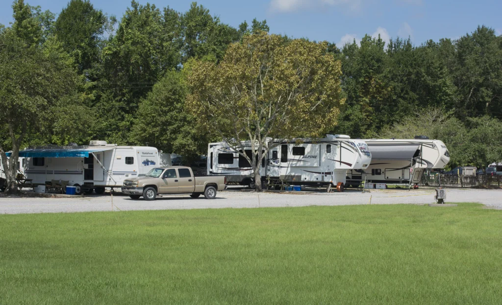 RVs and trailers parked at campground with pickup truck and shaded sites