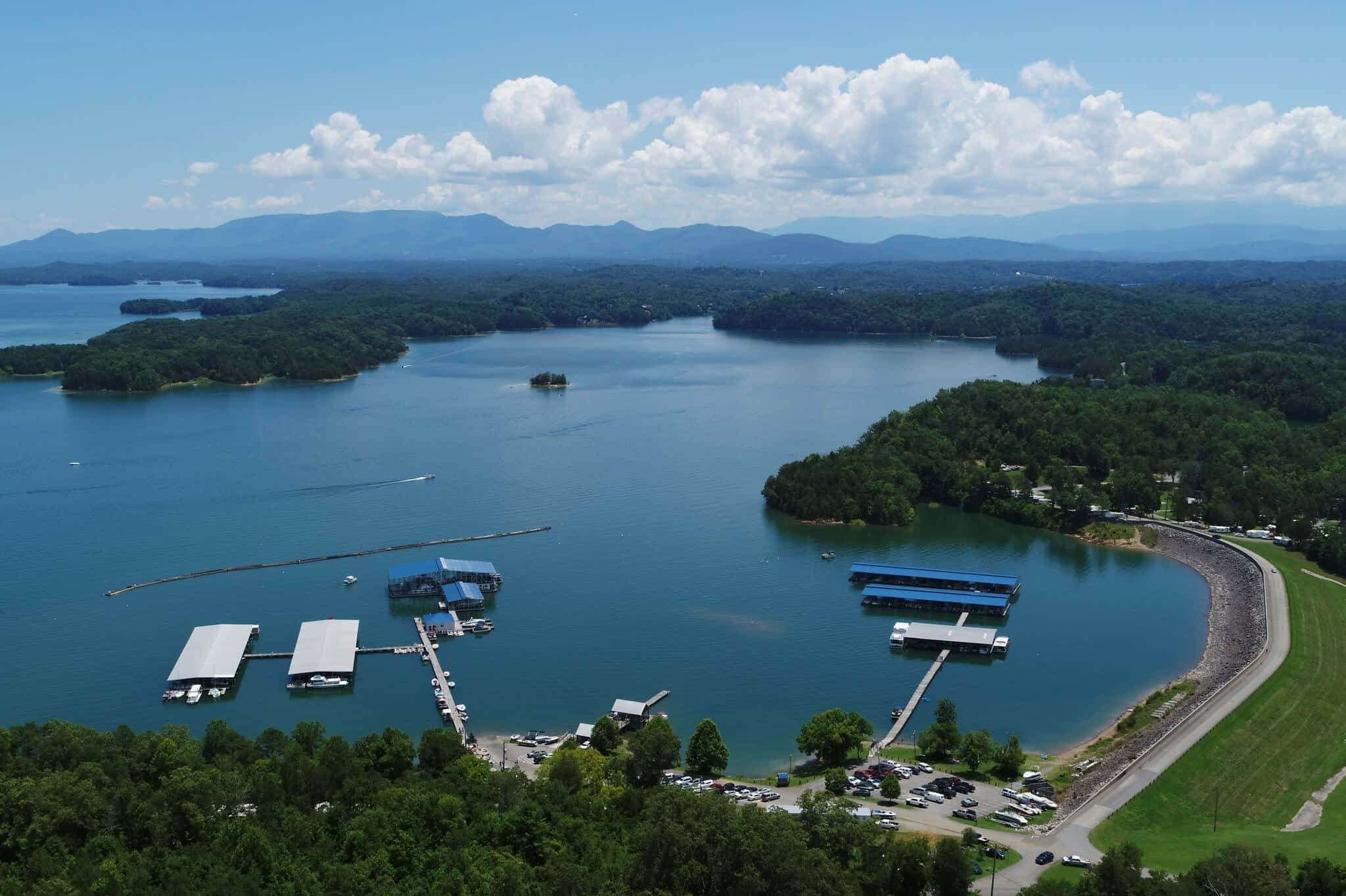 Aerial view of Douglas Lake with marina docks, forested shoreline, and the Great Smoky Mountains in the distance.