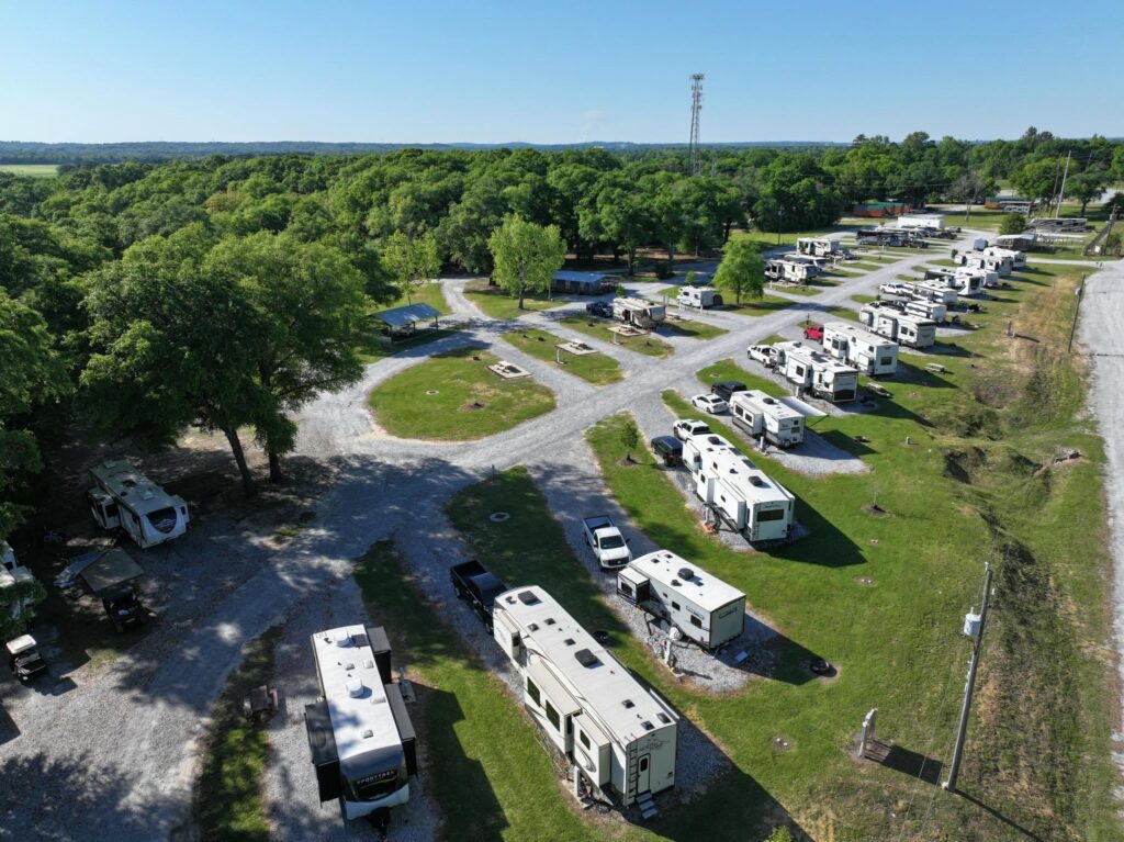 Aerial view of Camp David RV Resort featuring spacious RV sites, tree-lined grounds, wide roads, and scenic surroundings for a relaxing camping experience.