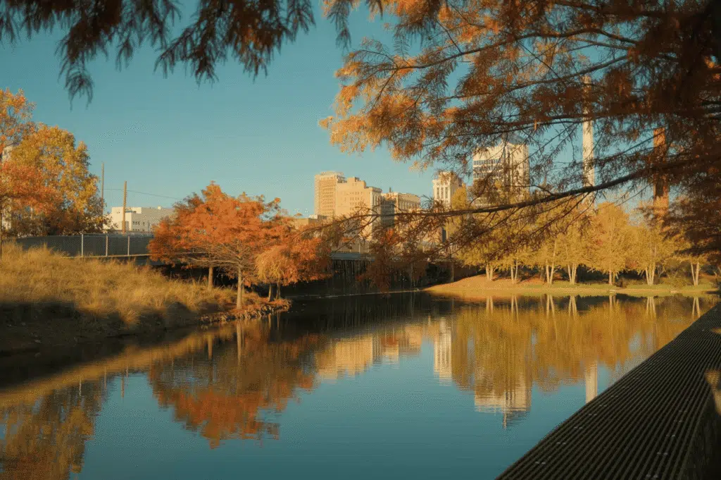 Downtown Birmingham, AL skyline reflected in a calm park pond framed by autumn foliage